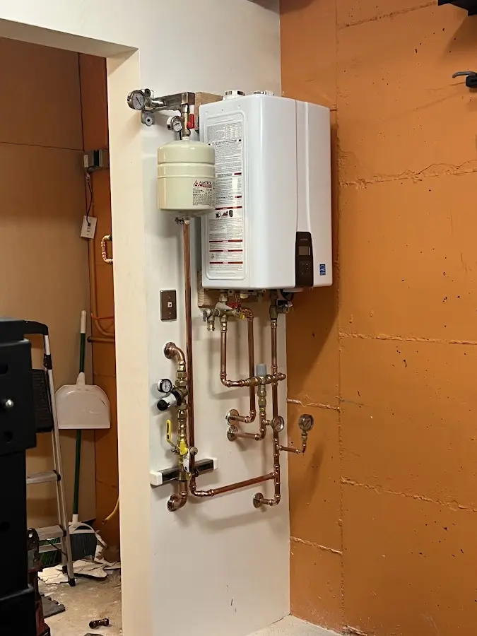 Plumbing technician inspecting water heater connections in Dumont